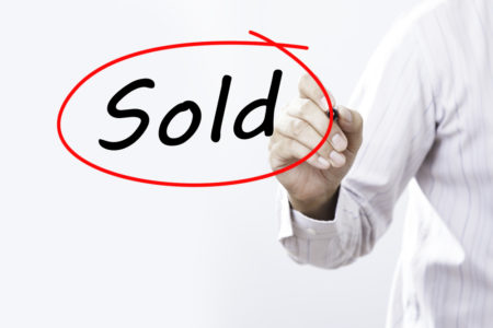 Businessman Hand Writing Sold with a marker over transparent board, Business concept.