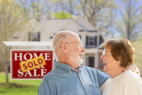 couple embrace in front of real estate sign